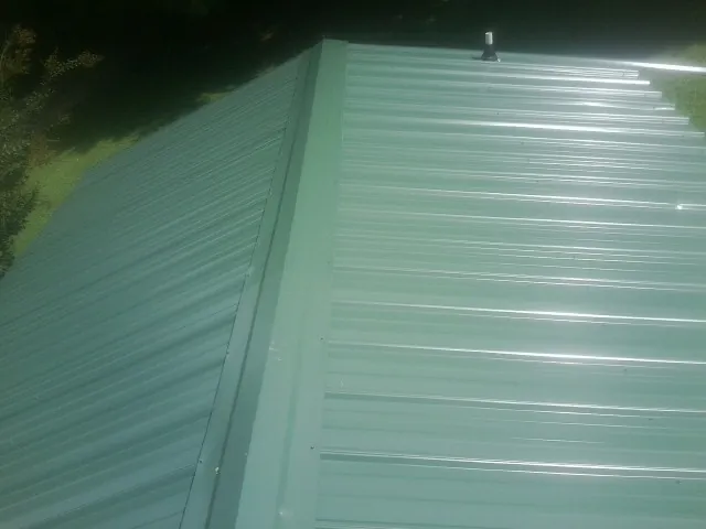 New green metal panels meeting at the ridge of a roof — Flat Roof Repair work by our crew in East Taunton