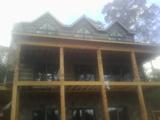 Dormers and porch framing on a large log home under construction — Roof Coating work by our crew in East Taunton