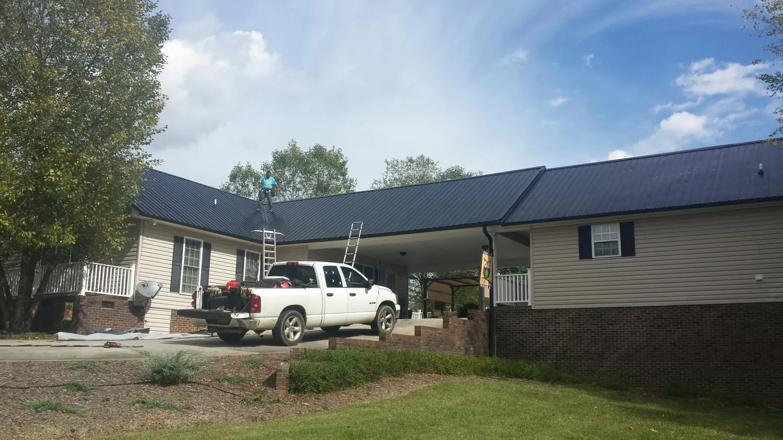 Black metal roof over a home and attached breezeway with ladders set in East Taunton
