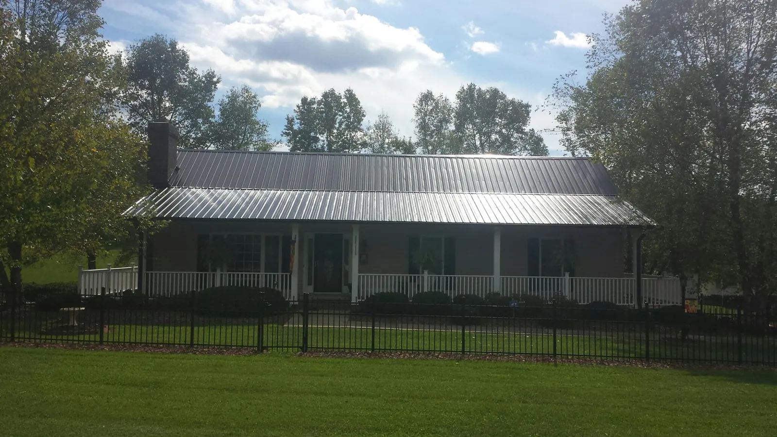 Gray metal roof on a brick ranch with a full width front porch — Gutter Guard Installation work by our crew in East Taunton