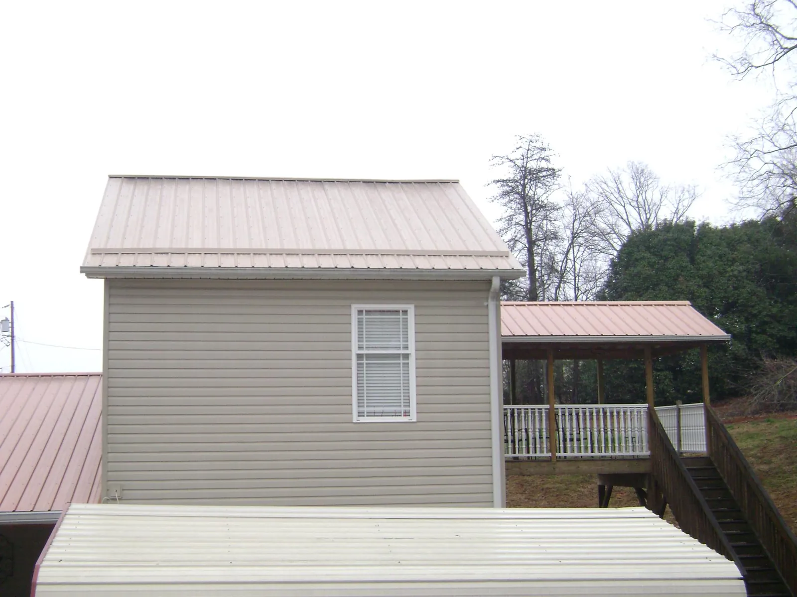 Tan metal roofs on a two story addition and attached porch, from a Roof Replacement job in East Taunton
